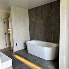 Bath on a lit plinth, dark wall