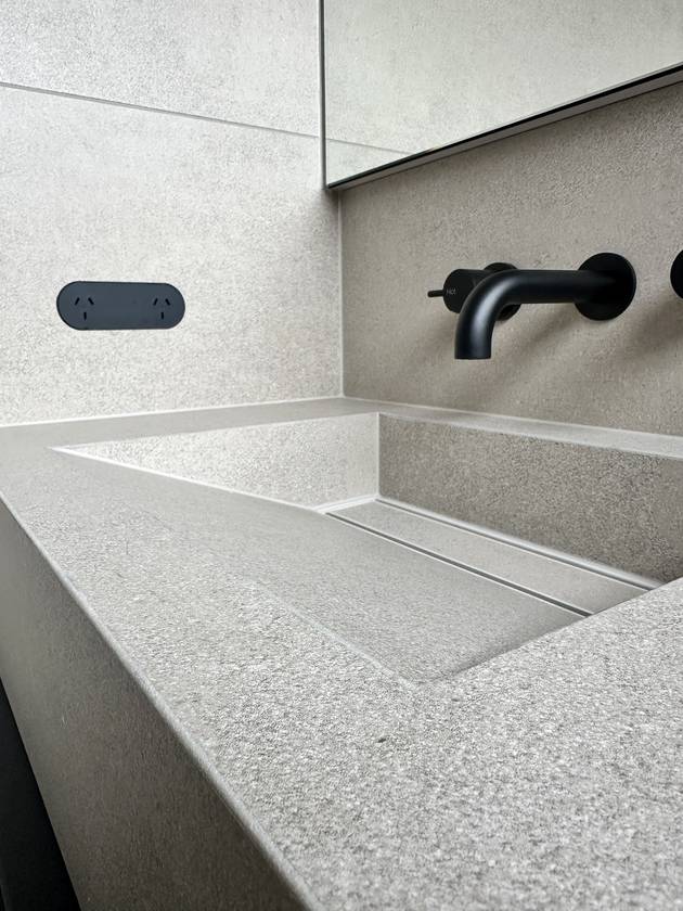 Tiled vanity basin: Cut from large porcelain slabs and sloped to a hidden slot drain.